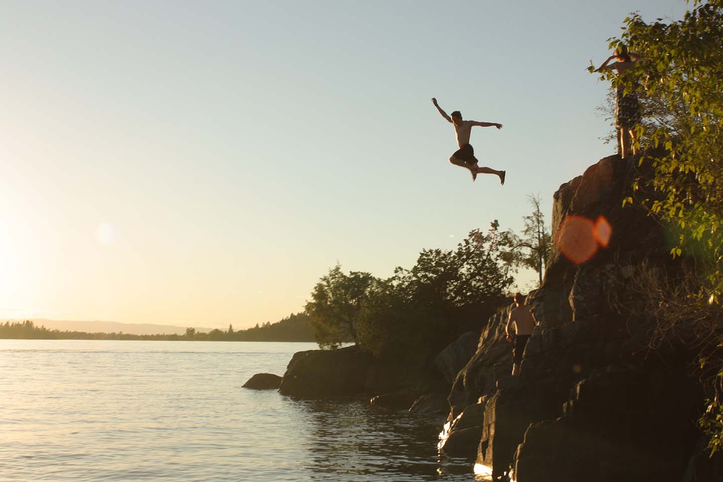 a man jumping into the water at sunset