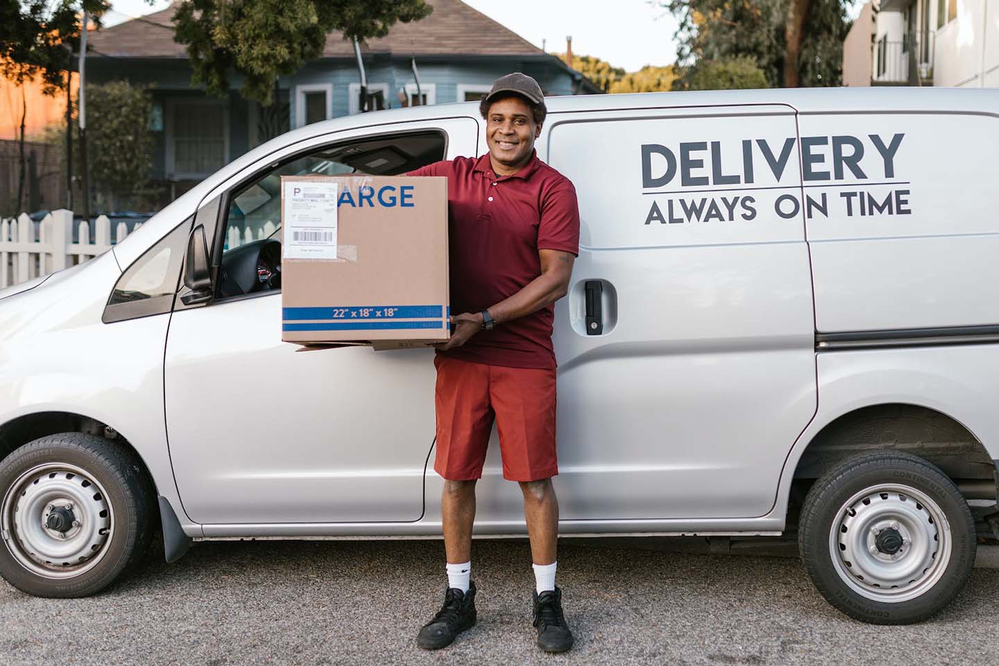 delivery man holding a large cardboard box in front of a delivery van