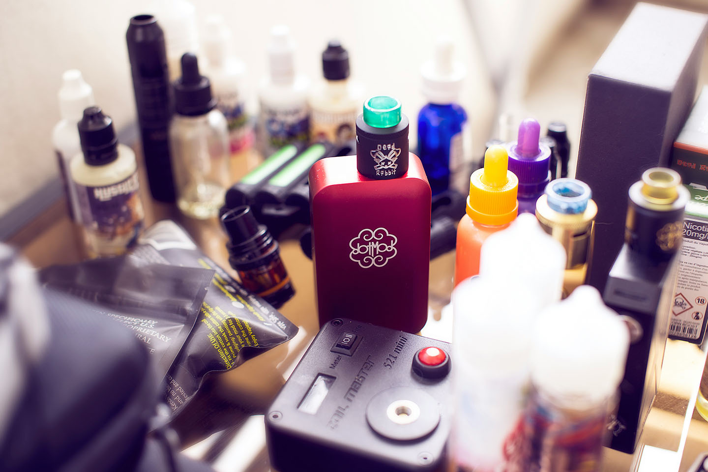 One vape device on a counter that's filled with a variety of dessert flavored e-juice.