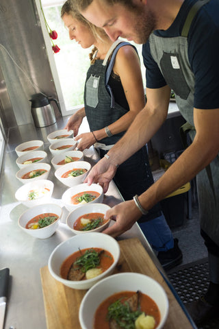 Zander Alt and Heidi Rentz add garnish to soup in handmade ceramic bowls.