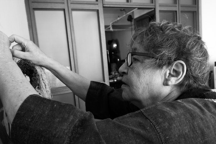 Andrea Aranow adjusts handmade textiles in her studio