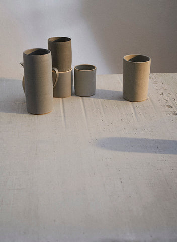 A grouping of handmade Sheldon Ceramics Cylinder Vases and Silverlake Tumblers in a variety of grey glazes. 