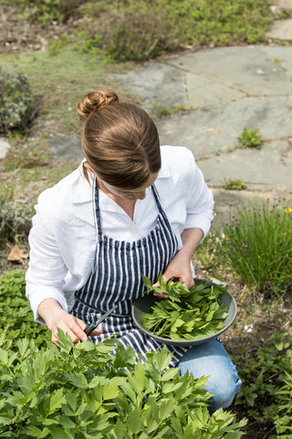 Annemarie Ahearn harvests parsley at Salt Water Farm, filling a handmade ceramic bowl with freshly snipped stems. 