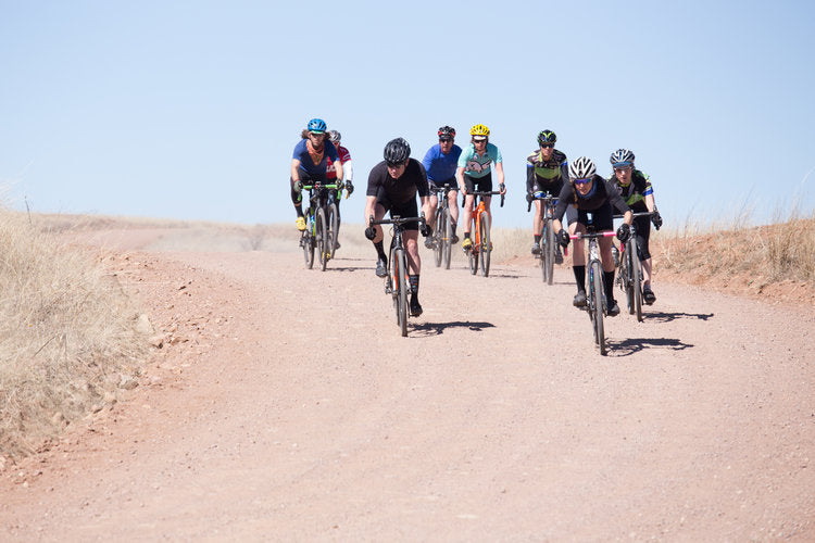 A group of Cyclist's Menu members ride bikes down a winding dirt path.