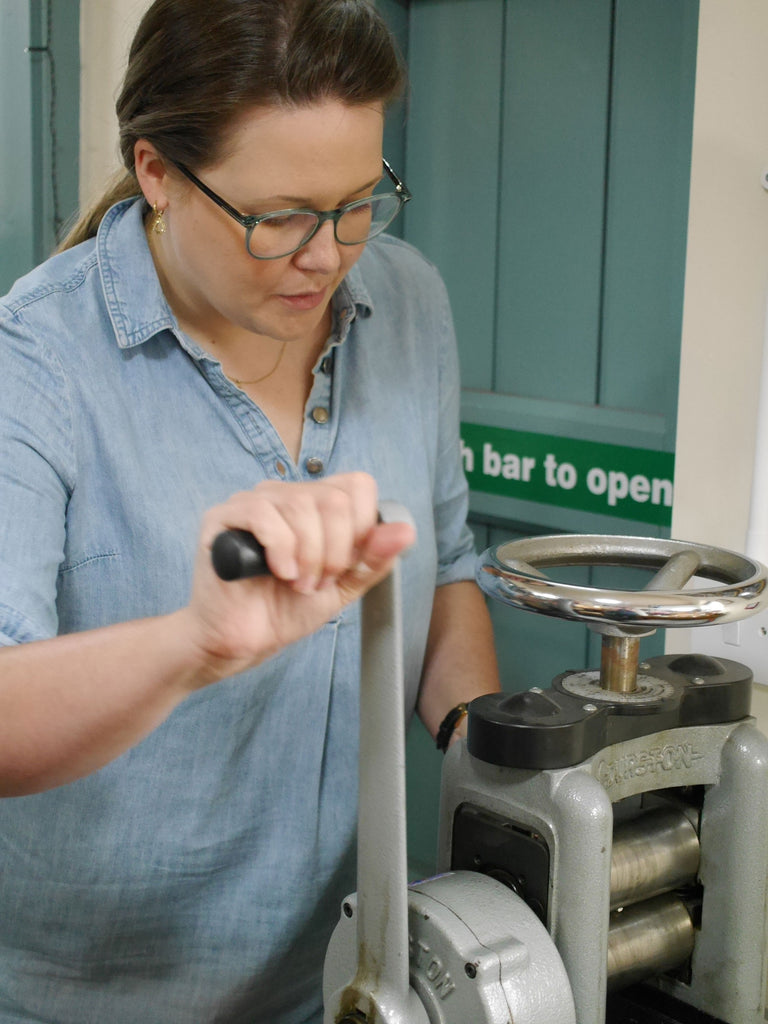 Hannah using the rolling mill to draw out her spoon handle