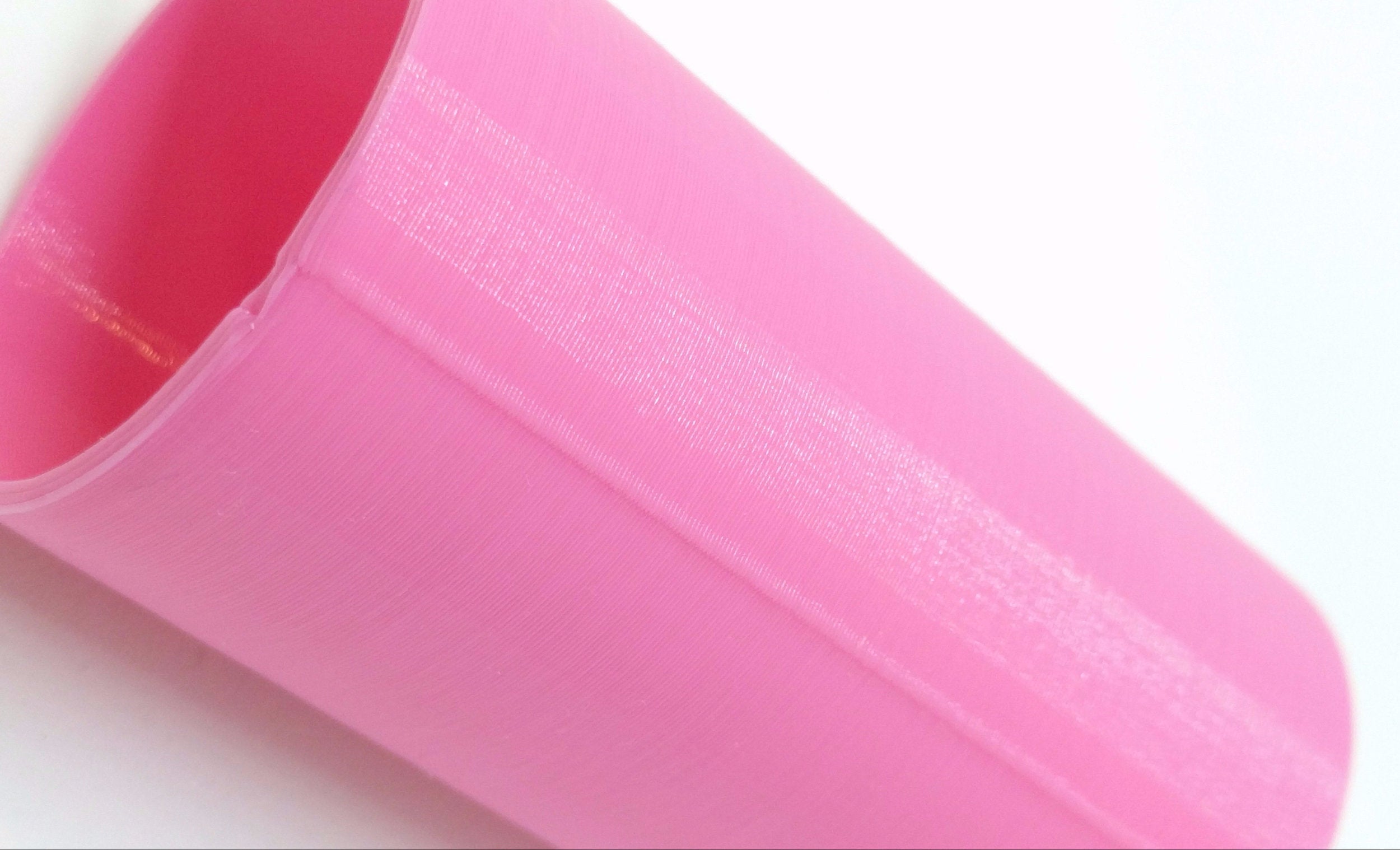 Pink 3D printed cylinder, focused on the layer seam