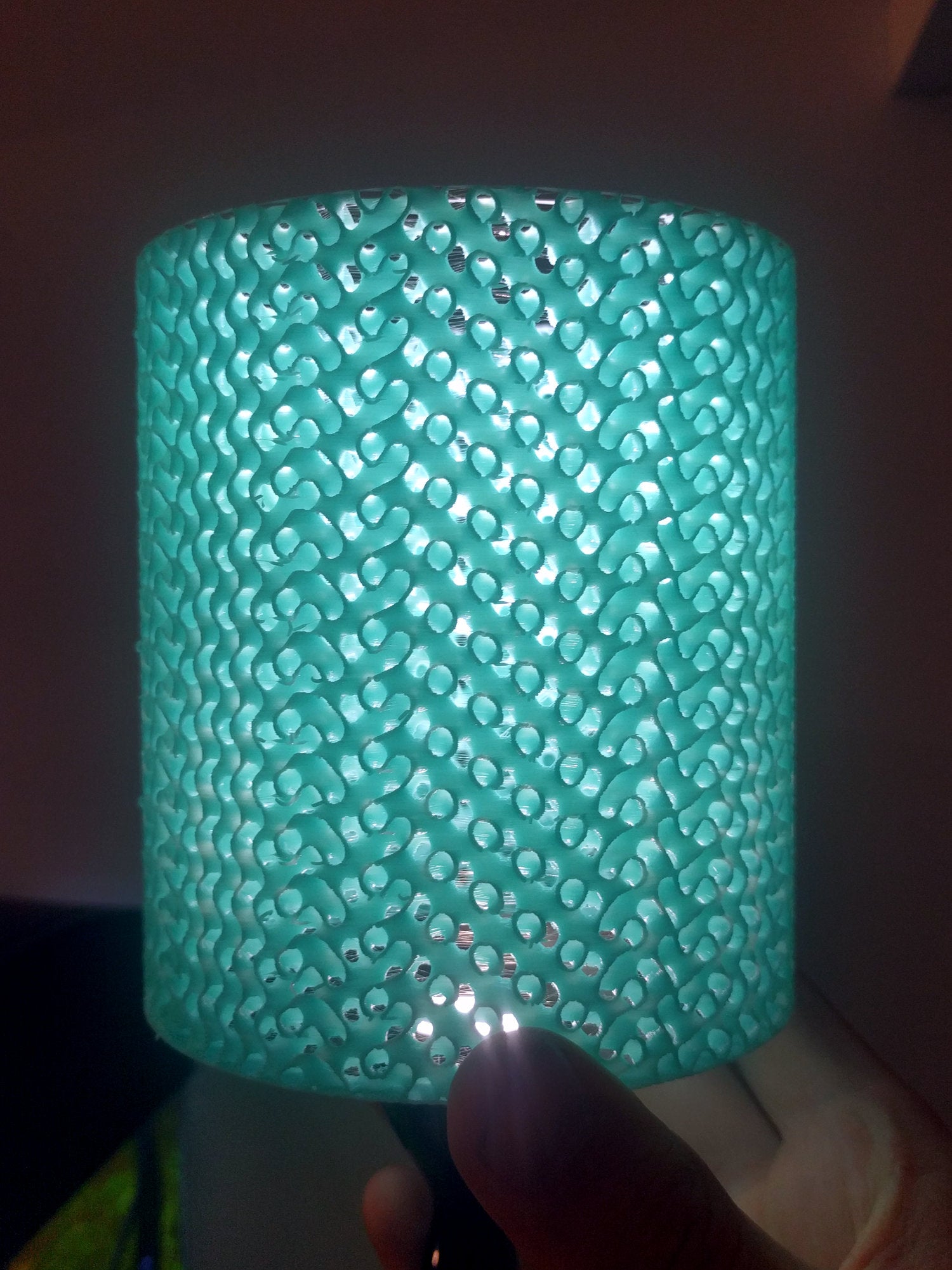 Blue cylinder printed with gyroid infill showing light shine through