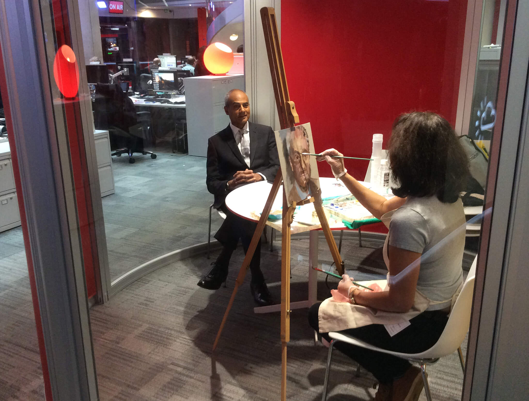 Artist Stella Tooth painting oil study on canvas board of BBC's George Alagiah in the BBC Newsroom.