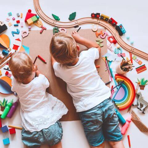 Caucasian boys playing with wooden toys on their tummy