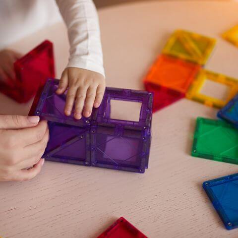 Hand building with magnetic tiles at a table