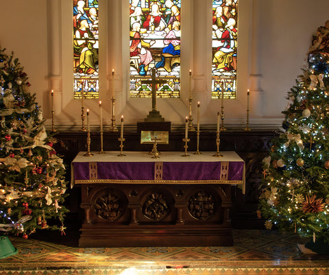 Autel d'une église avec 2 sapins de Noël de chaque côté et des vitraux en fond