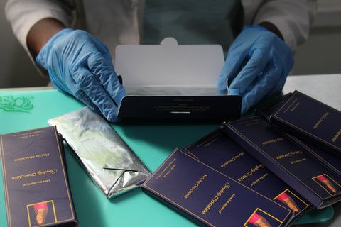 Pictured: a chocolate bar being wrapped in our signature royal blue label by a Simplicity Chocolate team member.