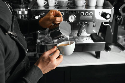 Taza de café de especialidad con la leche perfectamente cremada en Kima Coffee. Cafés para cafeterías de especialidad