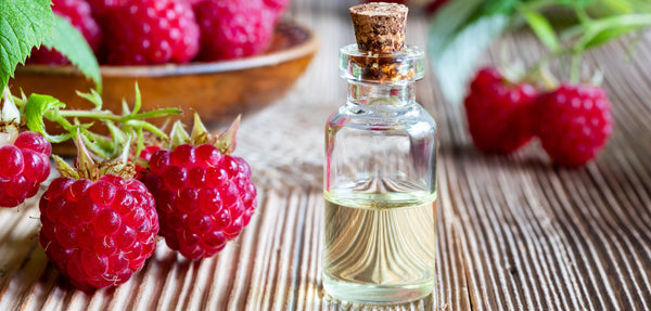 clear oil bottle with red raspberries