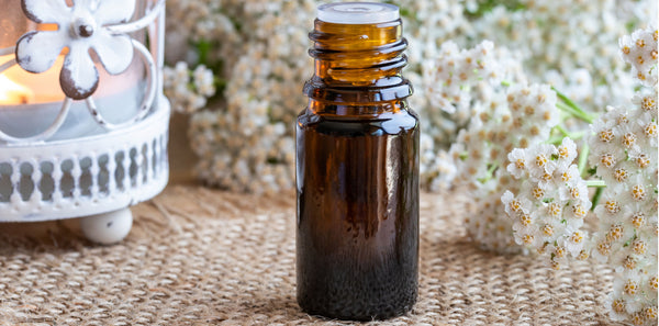 essential oil bottle with yarrow and candle