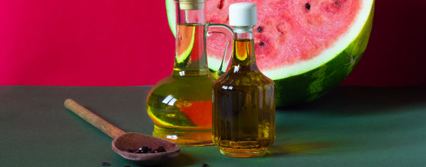 oil bottles with watermelon and seeds in spoon
