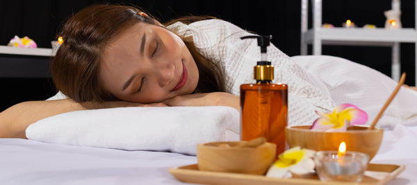 woman smiling while sleeping after massage with essential oil blend for sleep by massage supplies and candle