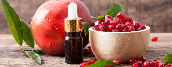 pomegrante fruit and seeds with essential oil bottle