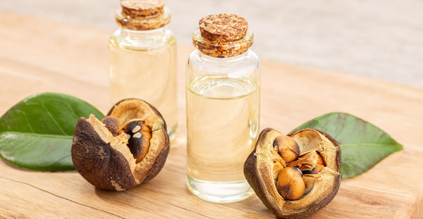 camellia oil in two bottles with flowers on wooden table