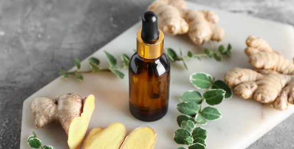 ginger essential oil bottle with ginger on cutting board