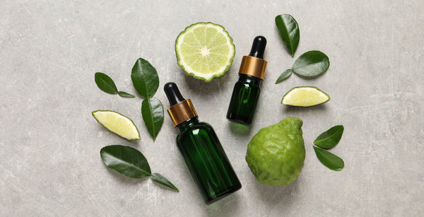 two bottles of bergamot essential oil with leaves and sliced fruit