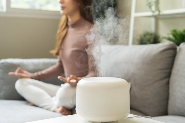 woman meditating with essential oil diffuser