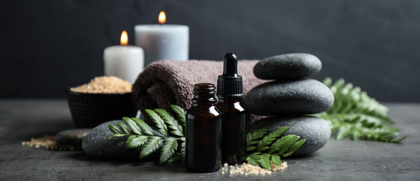 two bottles of vetiver essential oil with candles stones and bath towels