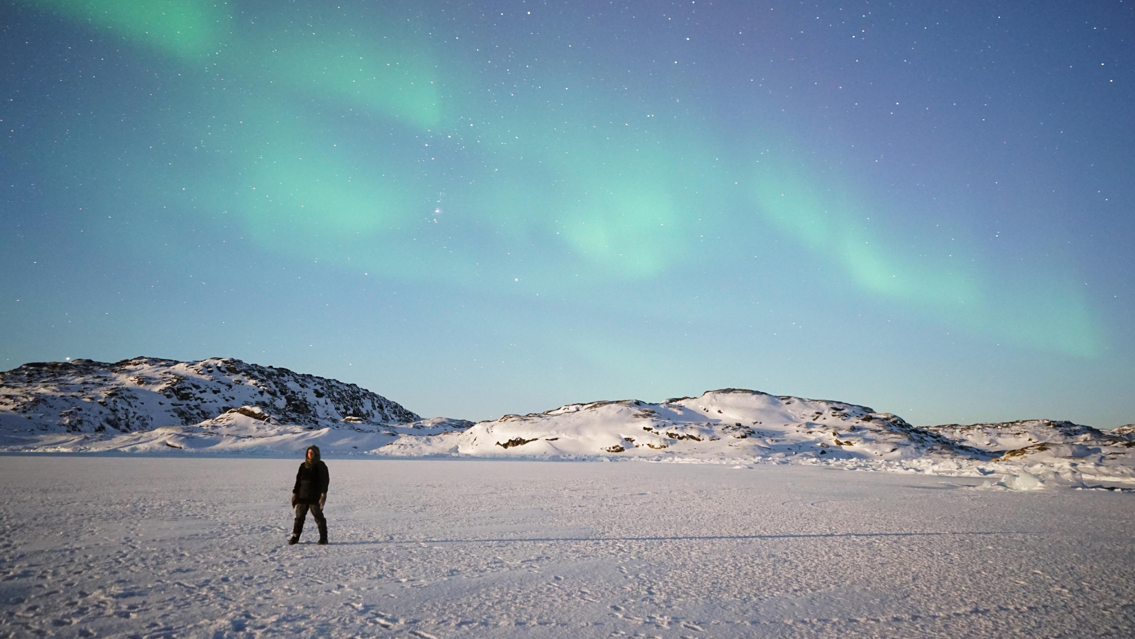 Femme dans l'immensité du Groenland et les aurores boréales