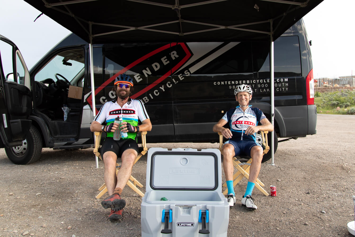 two men passing out water to cyclists