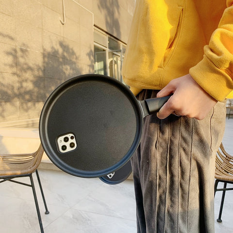 A person holding an innovative iPhone case with a black frying pan design.