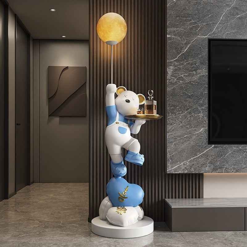 A whimsical sculpture of a stack of blue-and-white bears holding a serving tray, positioned in a modern room with gray marble walls and a warm glowing orb light, adds to the welcoming atmosphere.