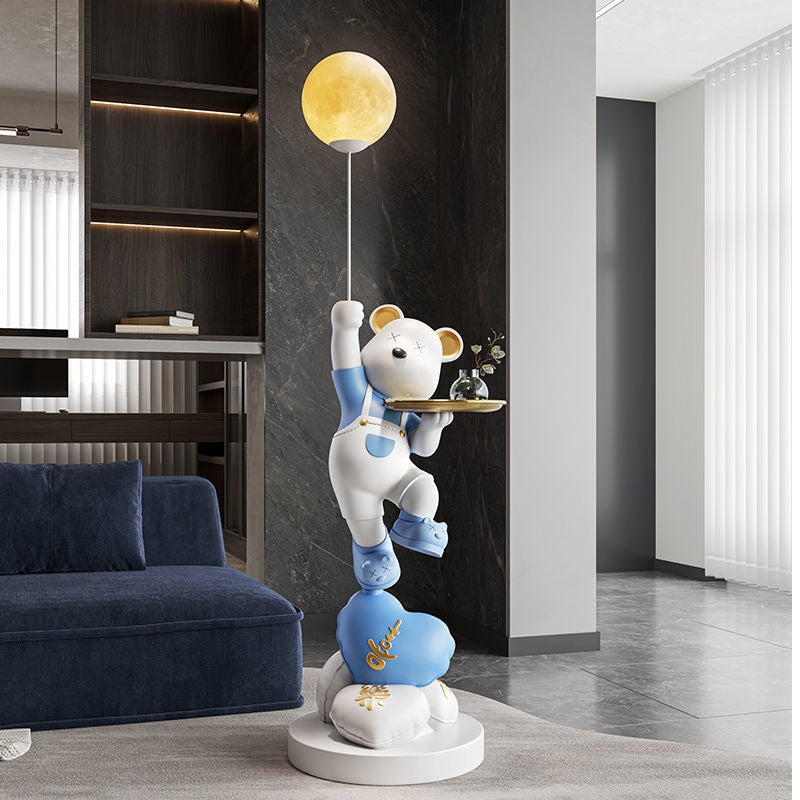 Decorative sculpture of an adorable bear climbing towards a yellow moon, displayed in a modern living room with sleek furniture.