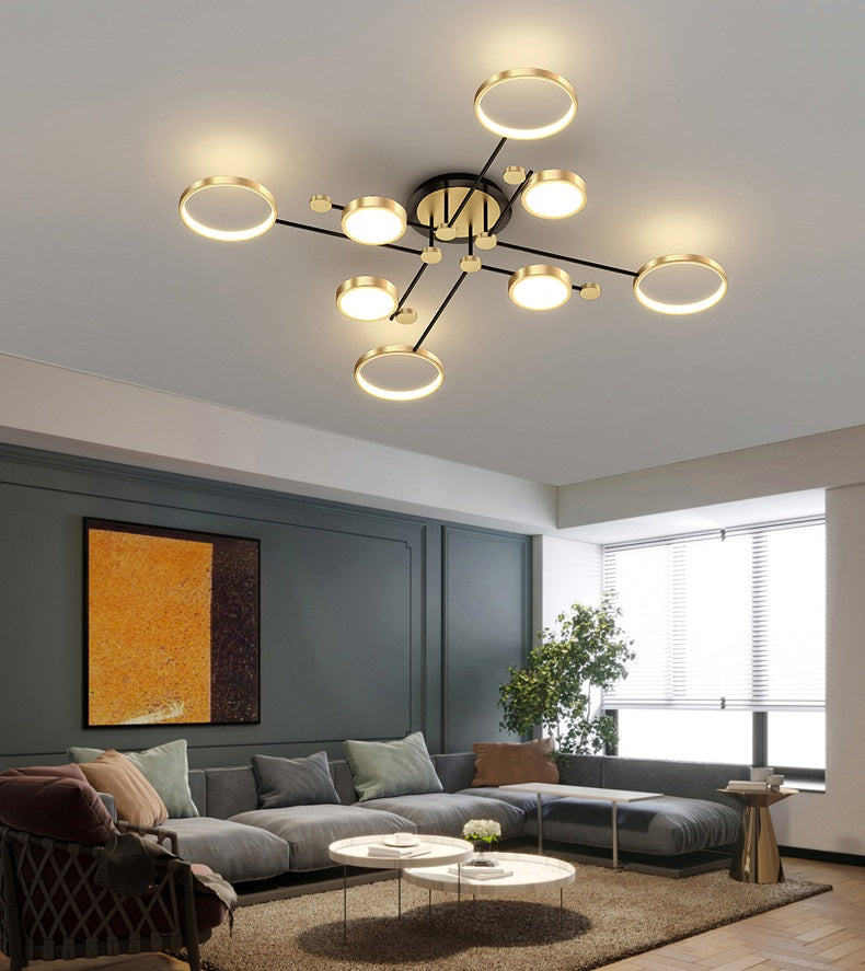 Modern living room with a stylish Atomic Starburst Ceiling Light, featuring multiple glowing bulbs. The room includes a cozy sofa, a coffee table, and abstract wall art.