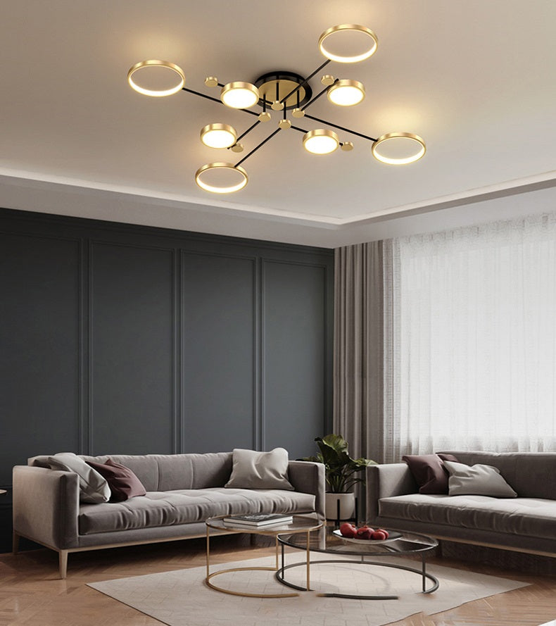 Modern living room with a gray sectional sofa, round glass coffee table, and an atomic starburst ceiling light.