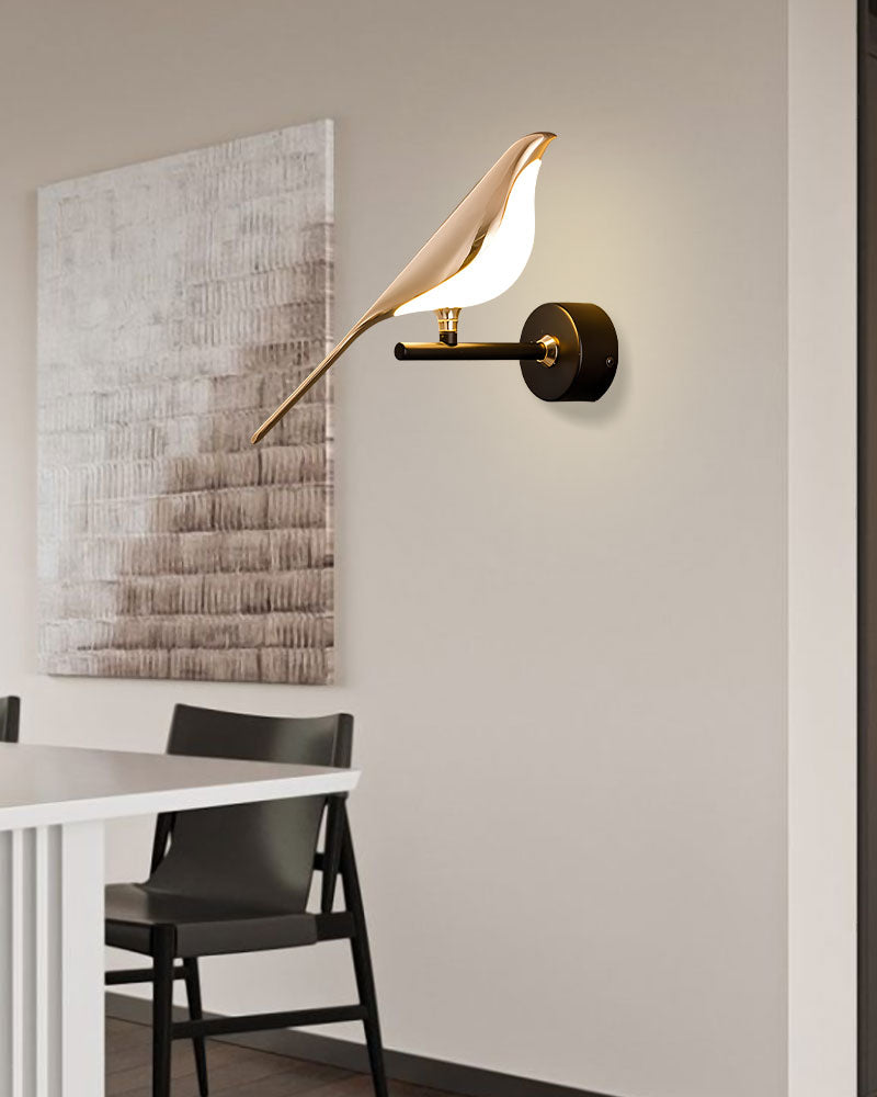 Wall-mounted light fixture, the Bird Wall Light, designed to resemble a bird perched on a branch, serves as an accent piece illuminating a modern dining area.