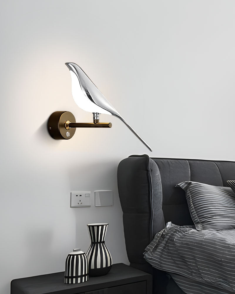 Modern bird wall light illuminating a grey room with a sofa and decorative items.