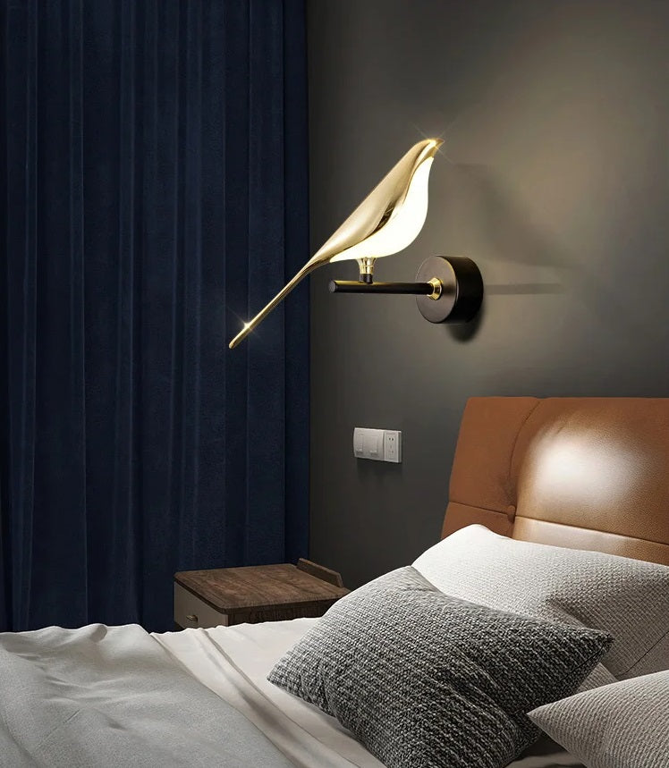 A stylish Bird Wall Light serves as an accent piece, illuminating above a modern bed with leather headboard and textured pillows.