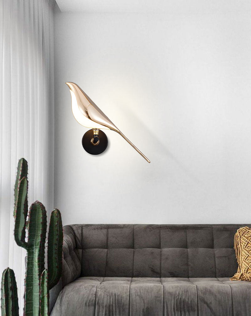 Wall-mounted Bird Wall Light above a grey sofa in a room with a cactus plant serves as an accent piece in interior design.
