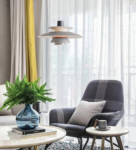 A living room with a grey couch and yellow chair adorned with a modern pendant light.