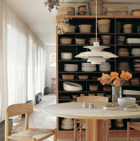 A dining room with a wooden table and chairs, styled with a pendant light.