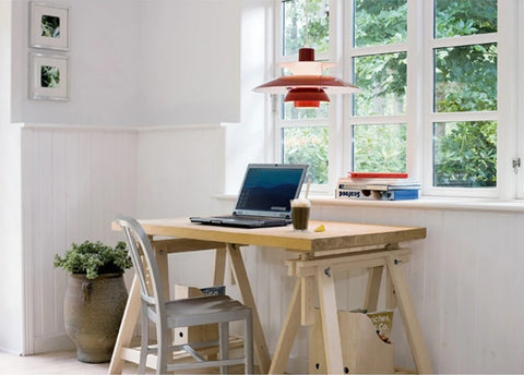 A stylish home office with a wooden desk and a pendant light.