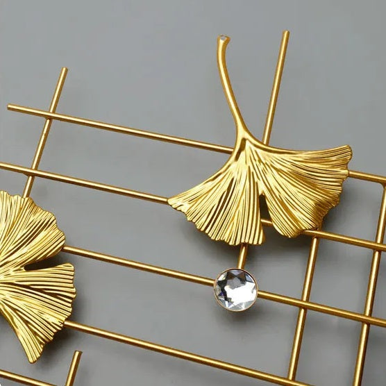 A pair of creative design gold leaf earrings with a crystal in the middle.