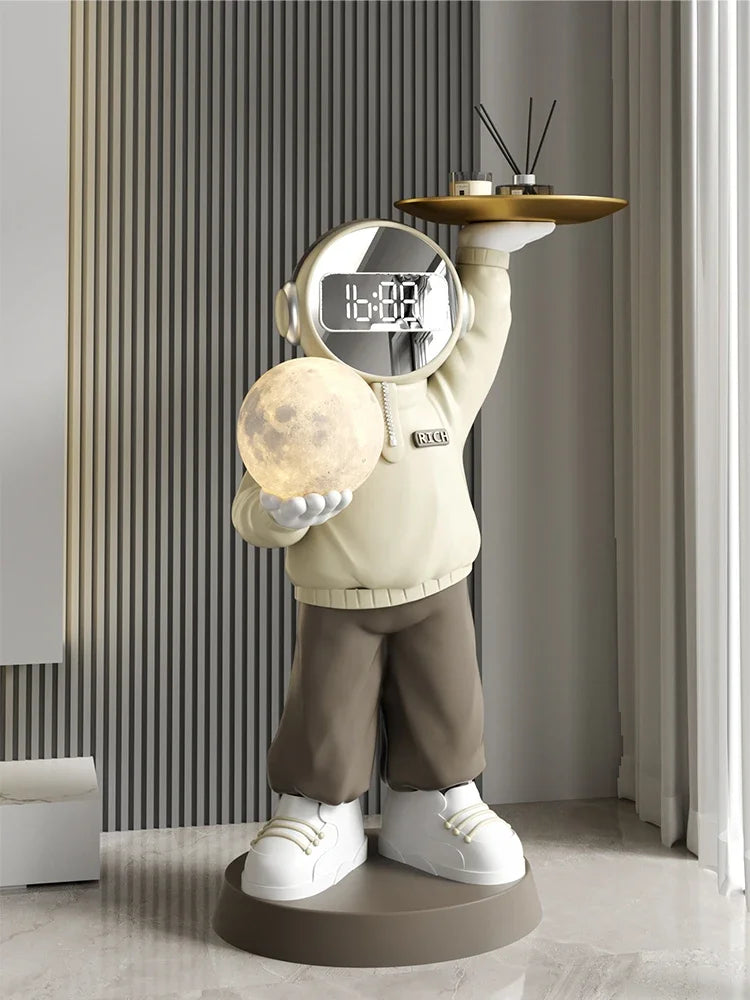 Statue of a cartoonish astronaut holding a soothing night light and a tray with a small plant and decorative items, positioned in a modern room with striped walls.