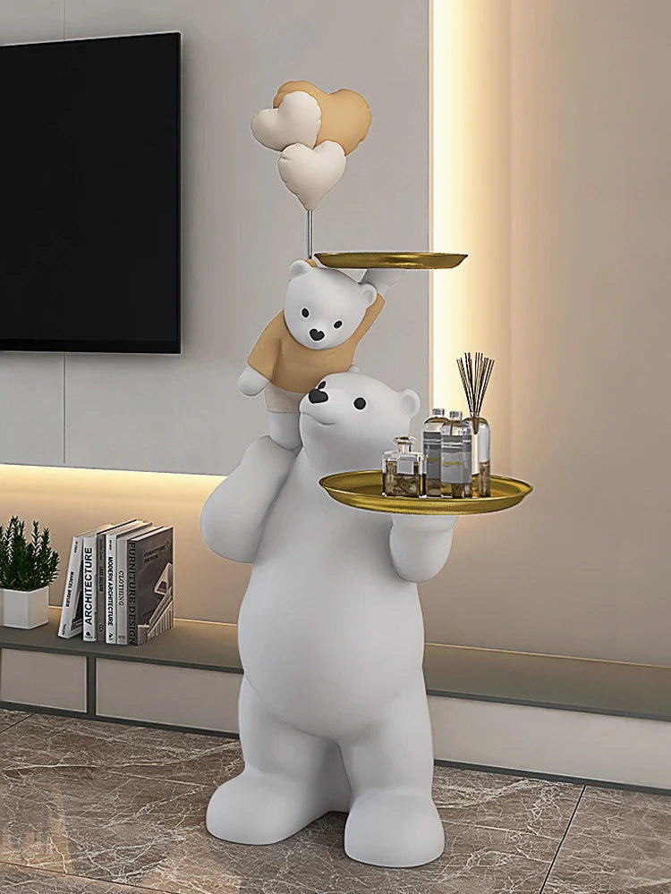 A whimsical sculpture of a polar bear holding a tray with a smaller bear on top, both in white, serving as a stylish centerpiece against a modern living room backdrop.