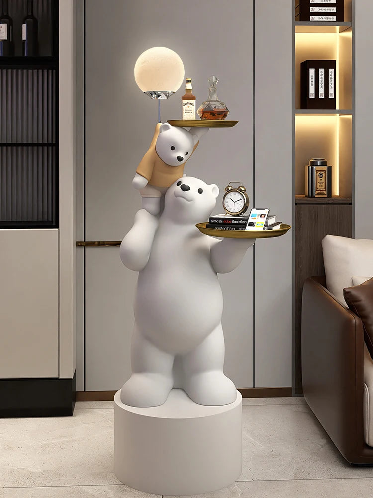 A whimsical floor lamp featuring a polar bear with a smaller bear on its shoulders, both holding a tray with a lamp and decorative items in a stylish living room.