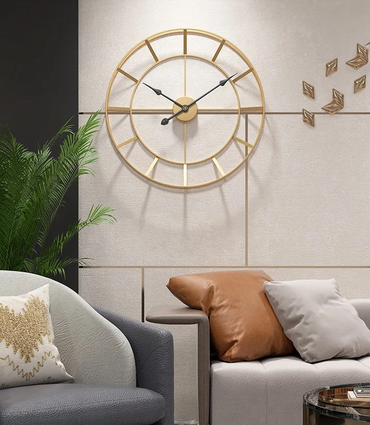 A modern gold geometric design wall clock above a sofa with decorative cushions in a minimalist decor living room setting.