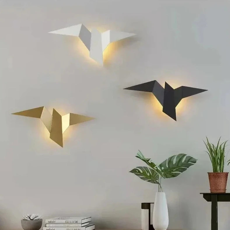 Three modern design origami-style bird-shaped wall lamps casting soft light on a neutral wall.