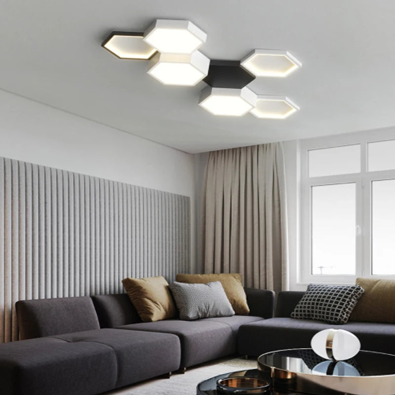 Modern living room with hexagonal ceiling light fixture above a gray sectional sofa, complemented by brown and gray cushions, and a sleek, round coffee table.