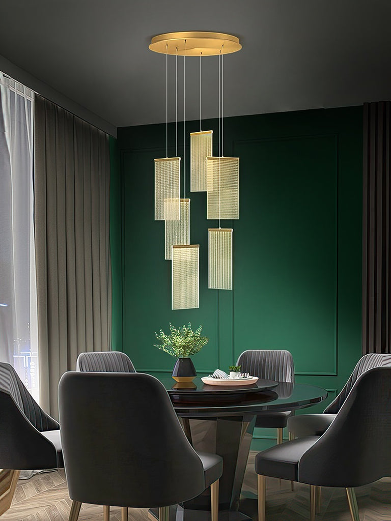 A luxurious dining room in a modern villa, featuring elegant green walls and a stunning chandelier.