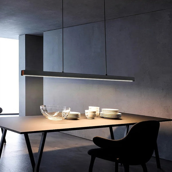 A sleek dining area with a table and chairs under the modern bar light.